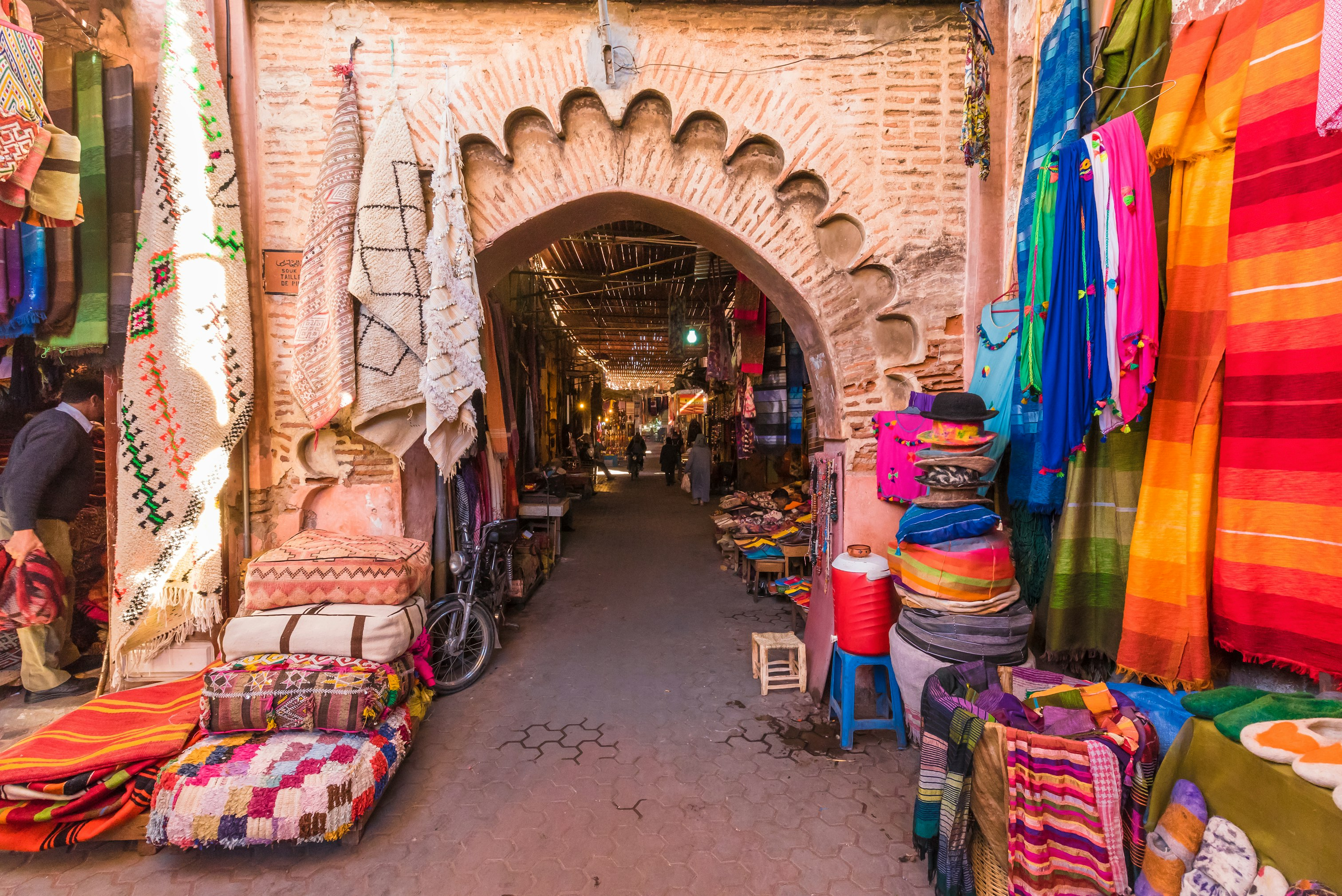 Gnawa musicians performing in a crowded Marrakech souk, surrounded by vibrant colors and rhythmic energy