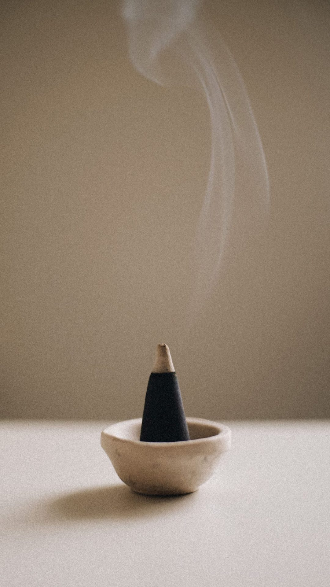 A traditional Moroccan woman carefully burning oud sticks in a ornate incense burner, surrounded by family members