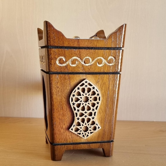 A bundle of oud sticks, carefully selected and prepared for burning, with intricate Arabic calligraphy in the background