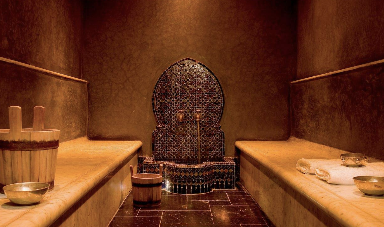 Interior of a traditional Moroccan hammam, with ornate tiles and steam-filled atmosphere