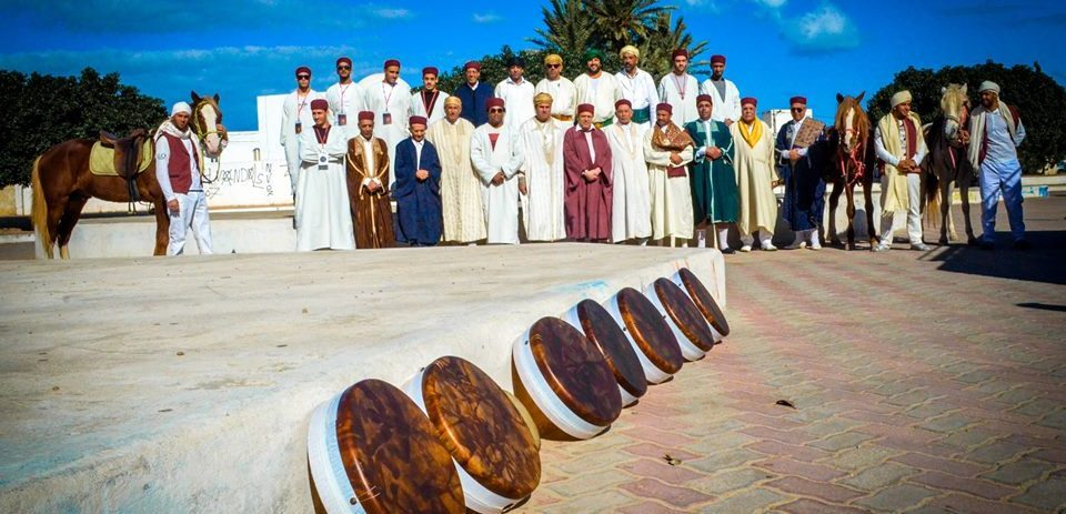A group of Sufi whirling dervishes in traditional attire, spinning in unison to the rhythm of the qraqeb
